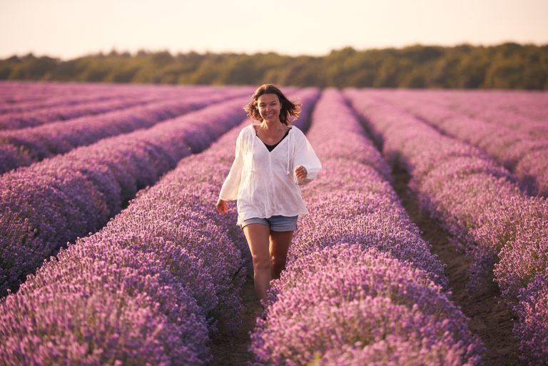 Young woman in white shirt in beautiful Lavender field at sunset